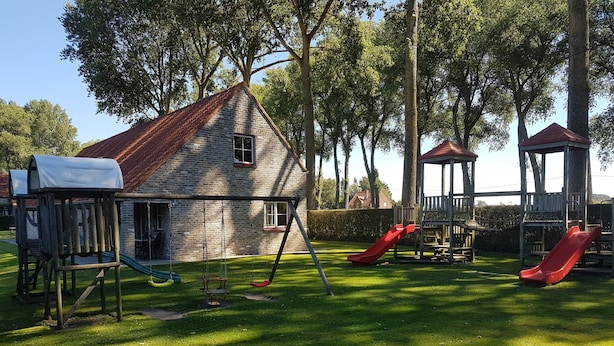 Een speeltuin met schommels, glijbanen en een klimrek.