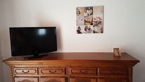 Een houten tv-meubel met een flatscreen televisie en een foto-collage aan de muur.