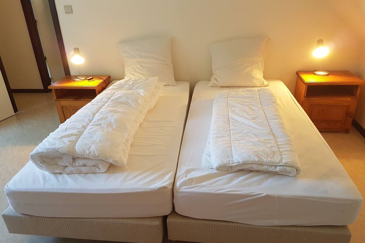 Ein Doppelbett mit weißer Bettwäsche und zwei Nachttische mit Lampen.