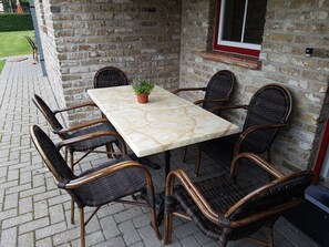 A patio with a marble table and wicker chairs.