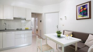 A modern kitchen with white cabinets, a dining table with a plant, and a brown sofa. - Lovely apartment in Rabac with WiFi (Rabac)