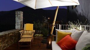 A wooden deck with a white sofa, a wicker chair, and a table with two wine glasses. - Guesthouse ai Santinelli (Capannori)