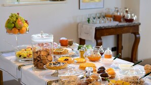 A buffet table with various food items and beverages, including fruits, pastries, and honey jars. - Guesthouse ai Santinelli (Capannori)