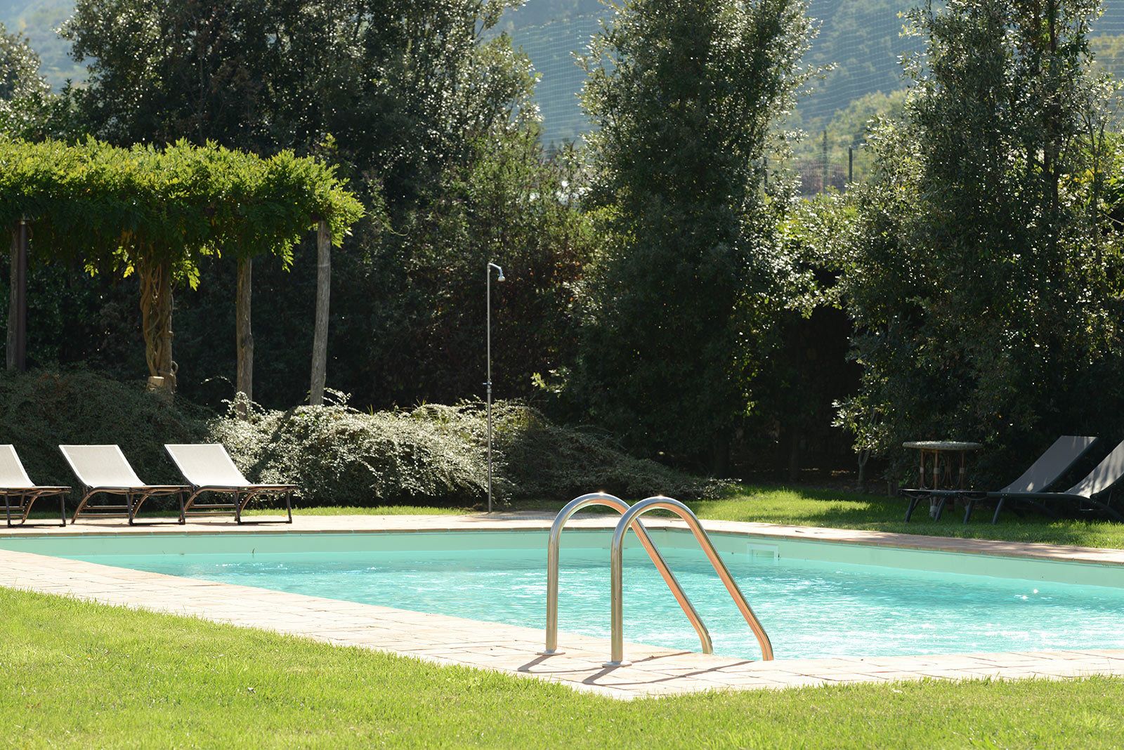 Une piscine équipée de chaises longues et d’un plongeoir métallique.