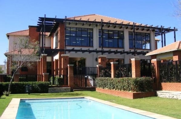 A two-story house with a swimming pool in the front yard.