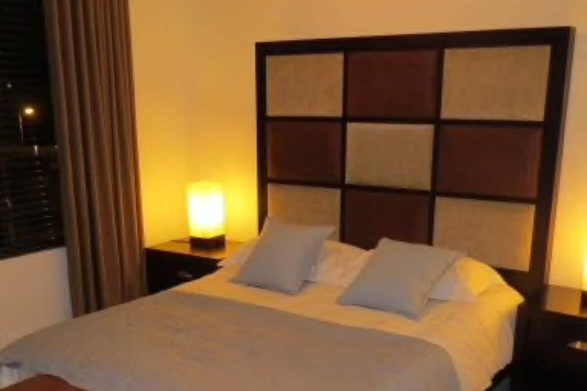 A large bed with a headboard, two bedside tables, and a bench.