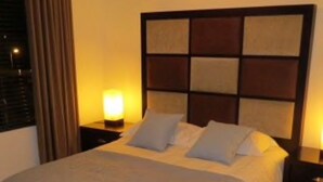 Ein großes Bett mit Kopfteil, zwei Nachttischen und einer Sitzbank.