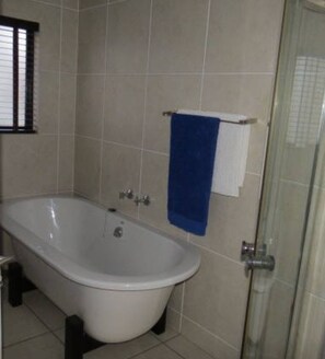 Une salle de bain avec une baignoire sur pieds, un porte-serviettes avec une serviette bleue et une porte de douche.