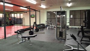 Ein Fitnessraum mit Krafttrainingsgeräten, Bänken und einer Spiegelwand.