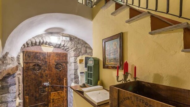 Un intérieur rustique agrémenté d’une arche en pierre, de portes en bois, d’un meuble vert et d’un lavabo en bois.