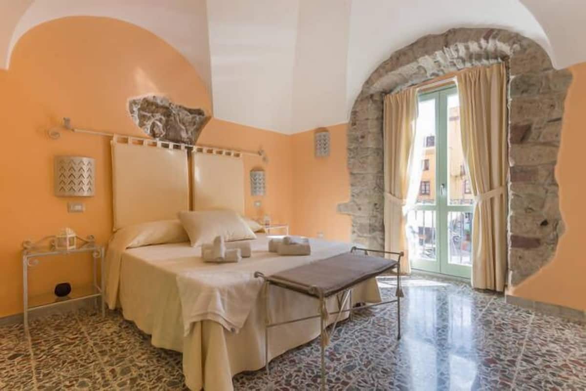 Une chambre à coucher avec un lit, une table de chevet, une lampe et un mur en pierre.