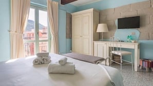 Une chambre d’hôtel avec un lit, un bureau, une chaise, une télévision et une fenêtre avec des rideaux.