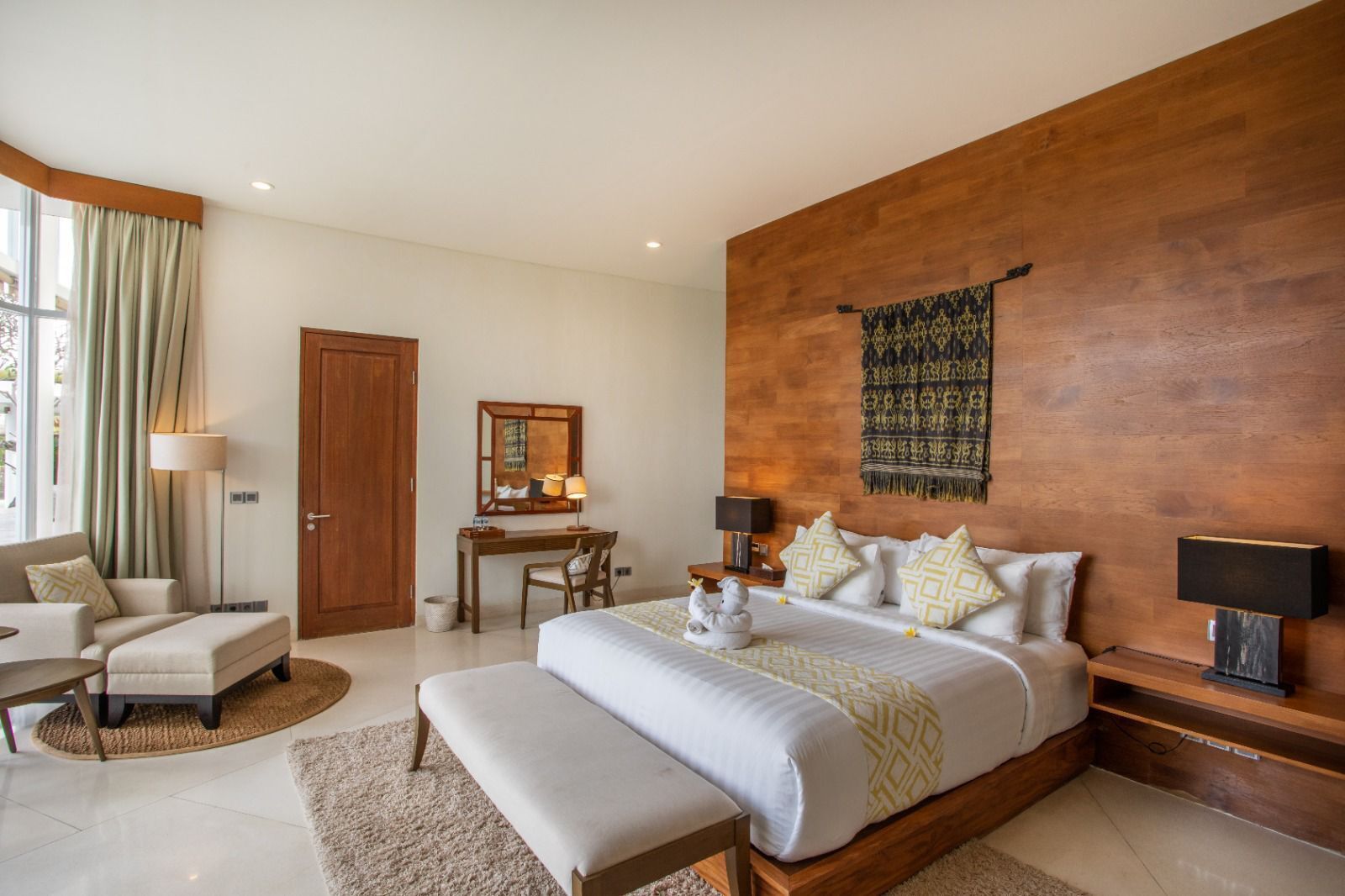 A modern bedroom with a large bed, a desk, a chair, and a sofa.