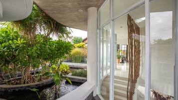 Un intérieur moderne avec un mur de verre, un petit élément décoratif aquatique et des plantes d’intérieur.