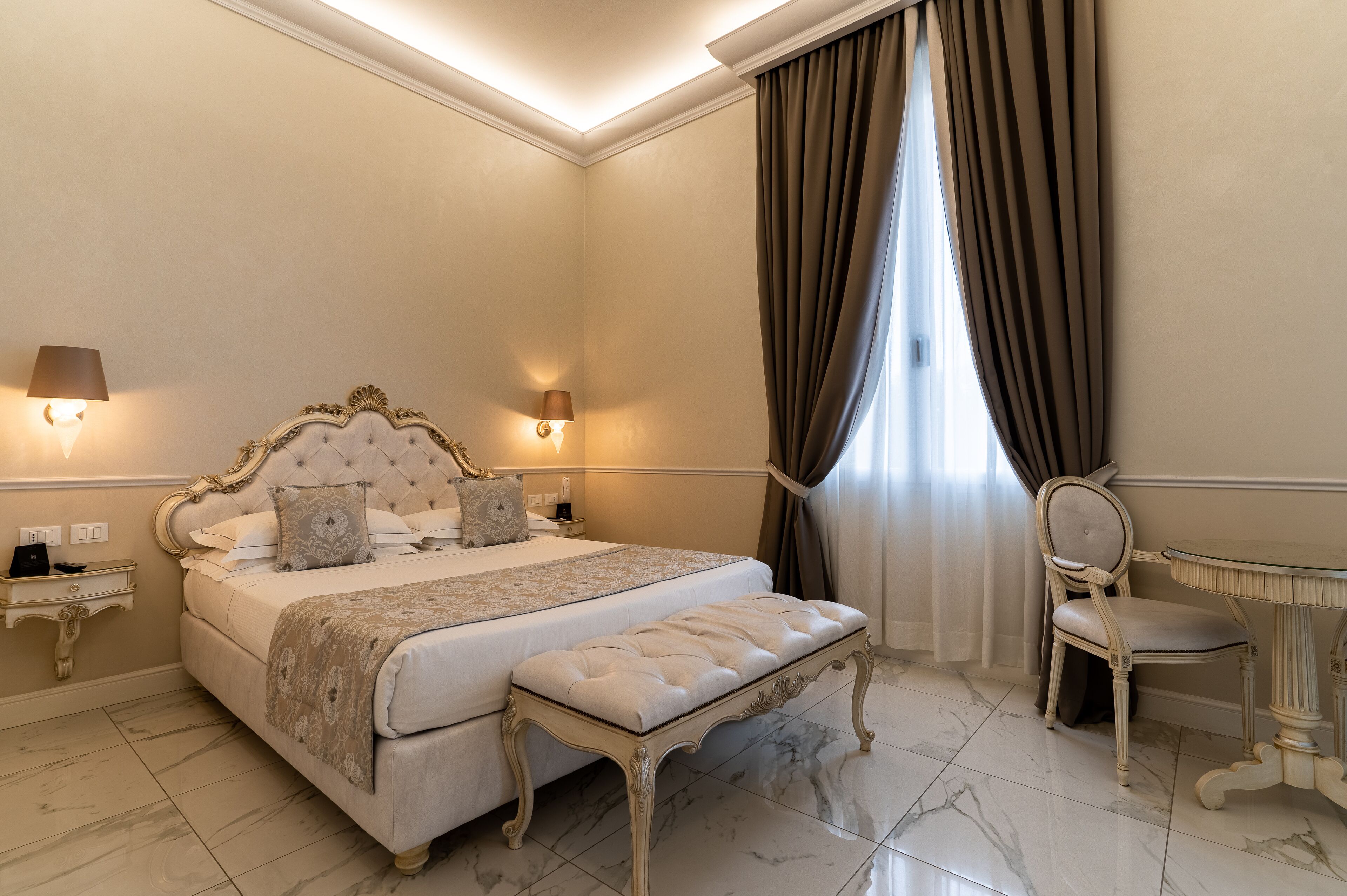 A bedroom with a large bed, bedside lamps, a chair, and a small table.