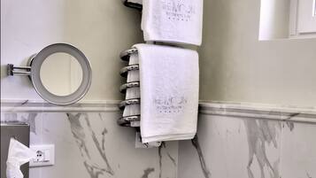 A bathroom with marble walls, a sink, a bidet, and a towel rack with two towels.