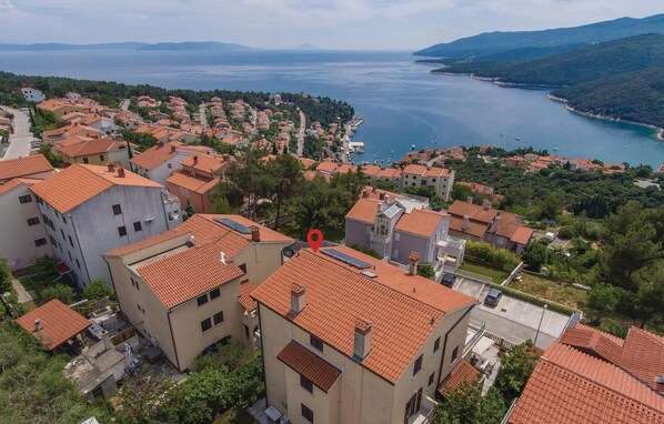 Un quartier résidentiel en bord de mer, avec des bâtiments aux toits de tuiles rouges, un port de plaisance et une vue sur la mer.