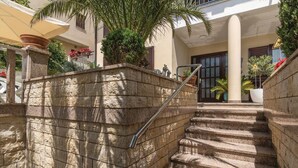 A stone staircase leading to a building entrance, with a metal handrail and potted plants along the sides. - Beach front apartment in Rabac with WiFi (Rabac)