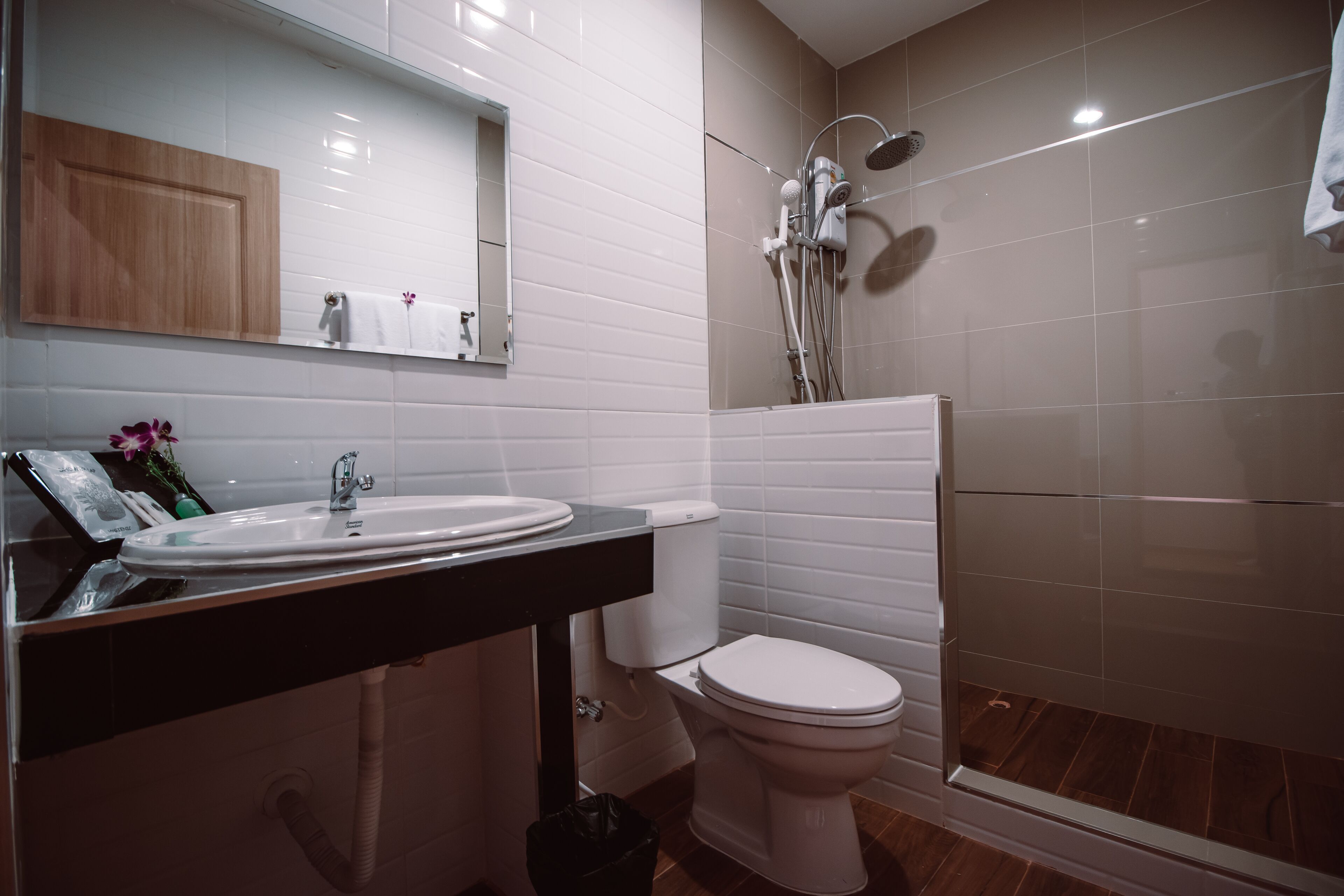 Een moderne badkamer met een wit wastafel, toilet en douche.