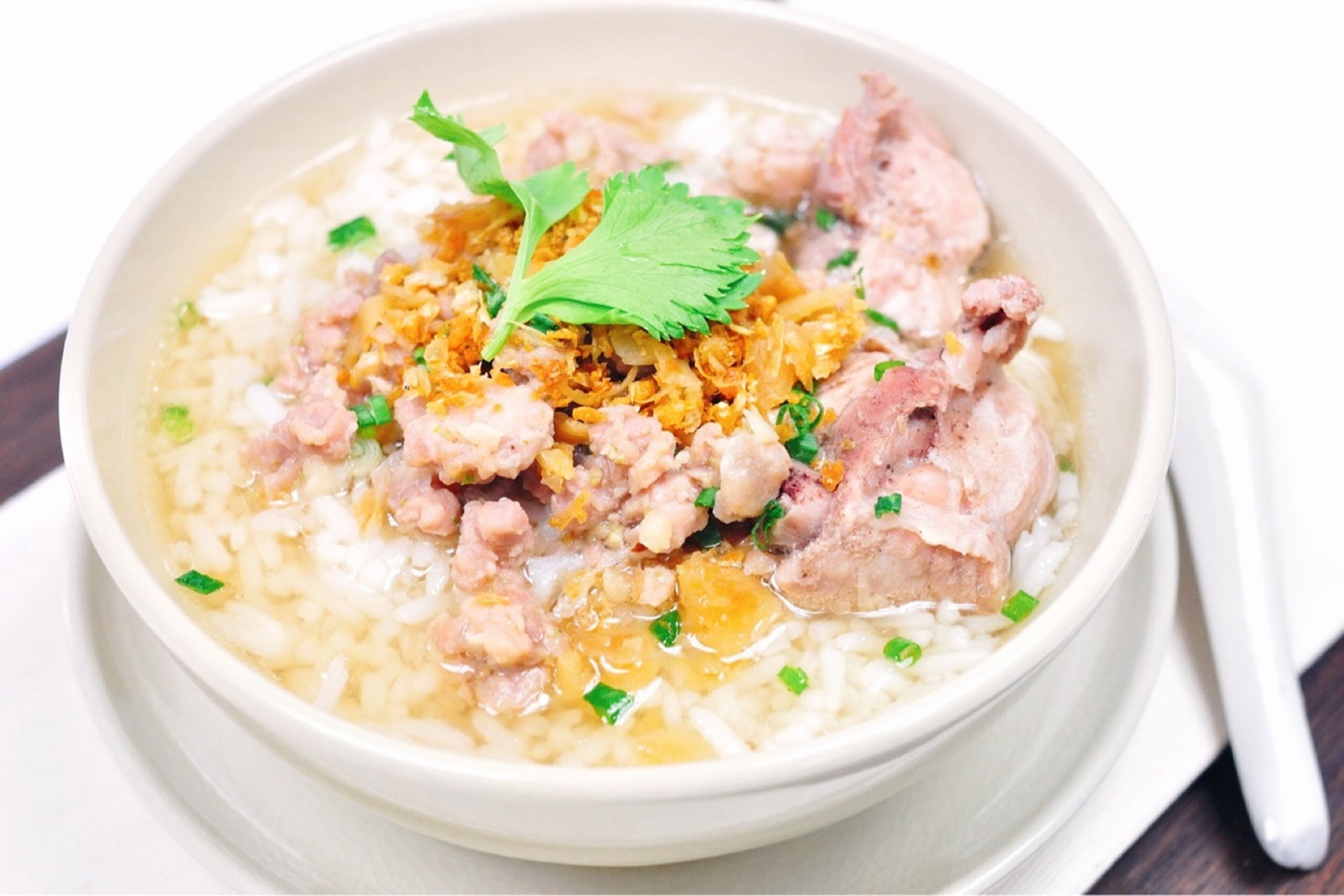 A bowl of soup with rice, chicken, and garnishes.