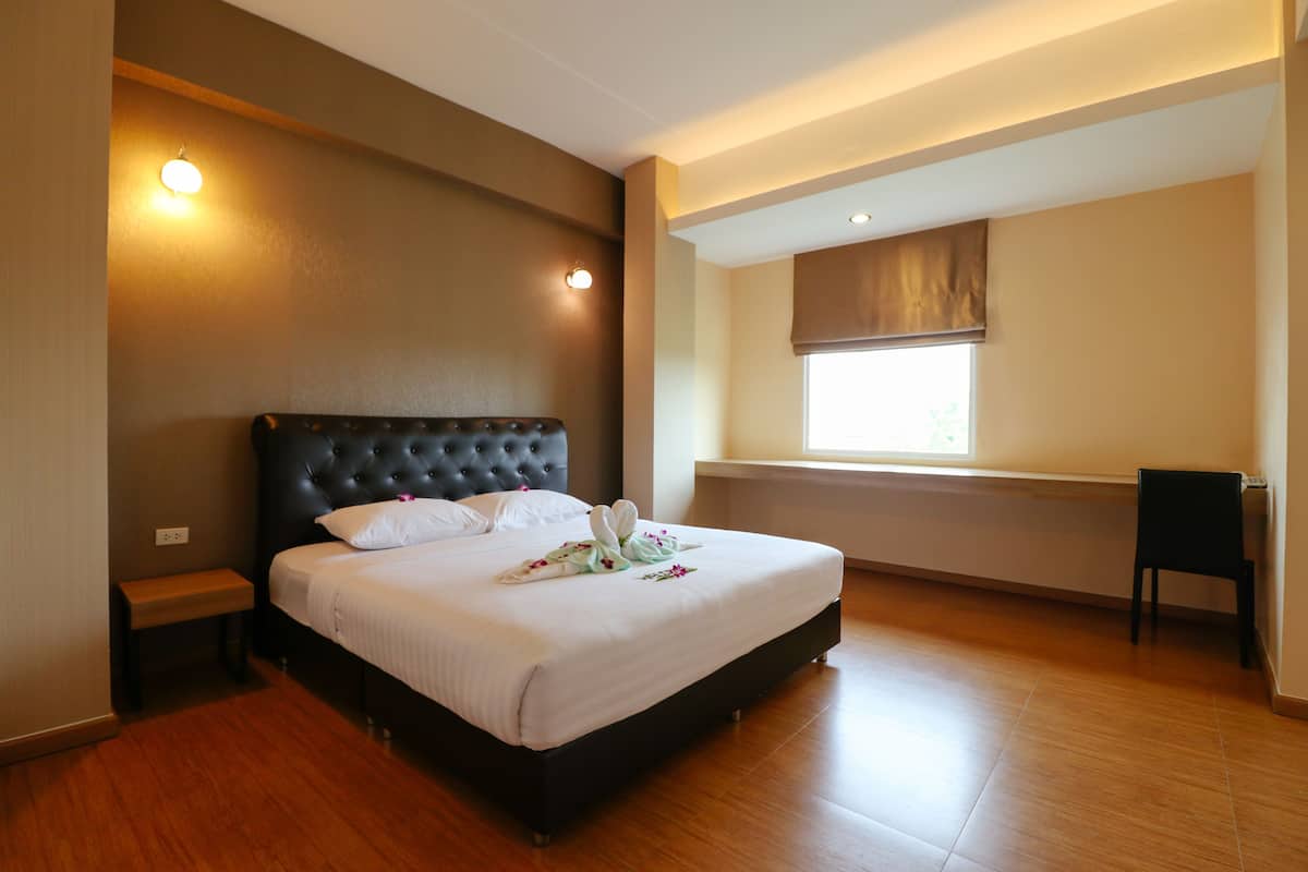 A bedroom with a large bed, a bench, a chair, and a window with a view.