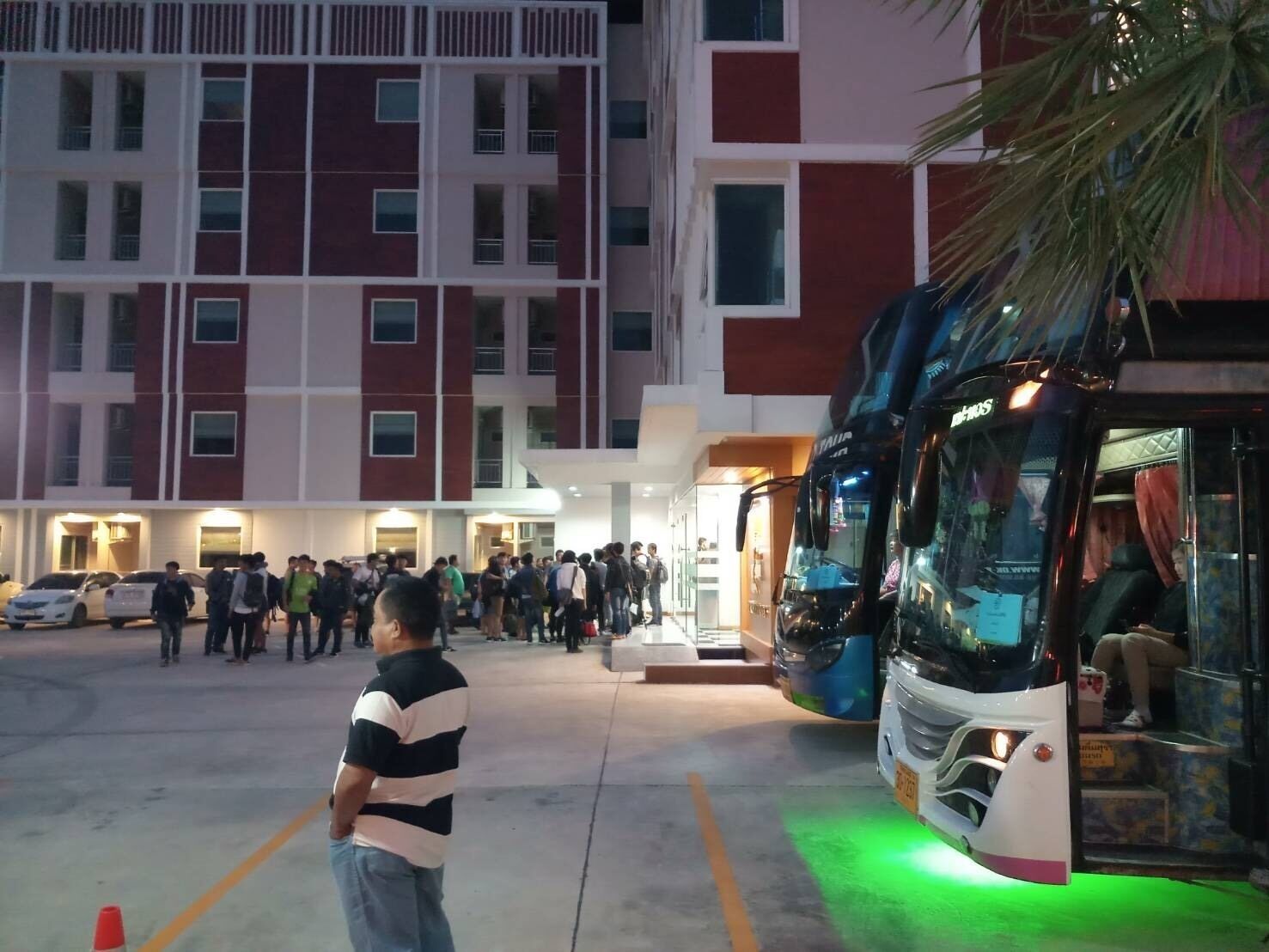 A building with multiple floors, a parking area, and a bus.