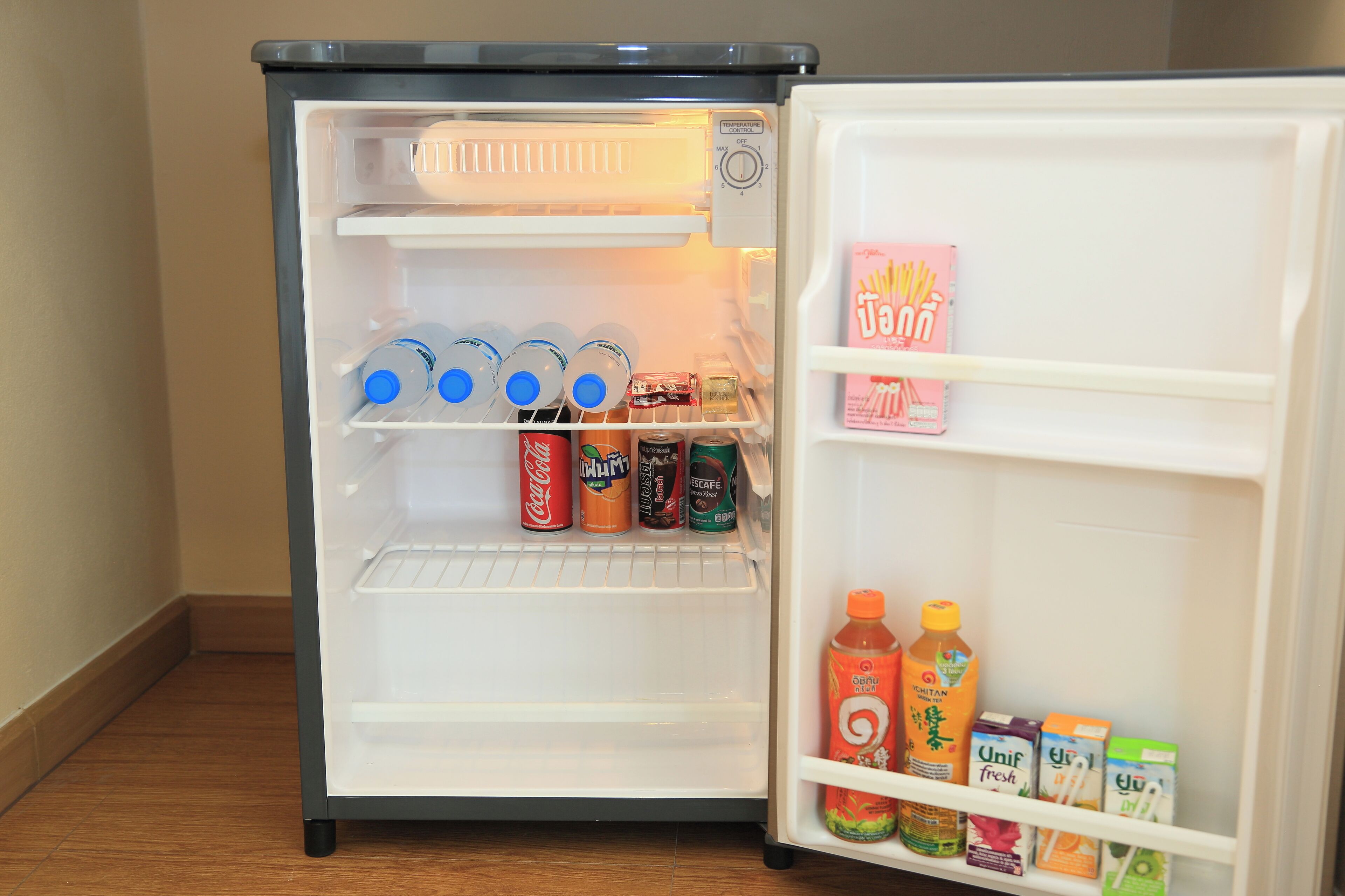 Un refrigerador con estantes llenos de bebidas y aperitivos.
