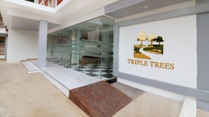 A modern building entrance with a glass facade, a checkered floor, and a "TRIPLE TREES" sign. - Triple Trees (Lam Luk Ka)