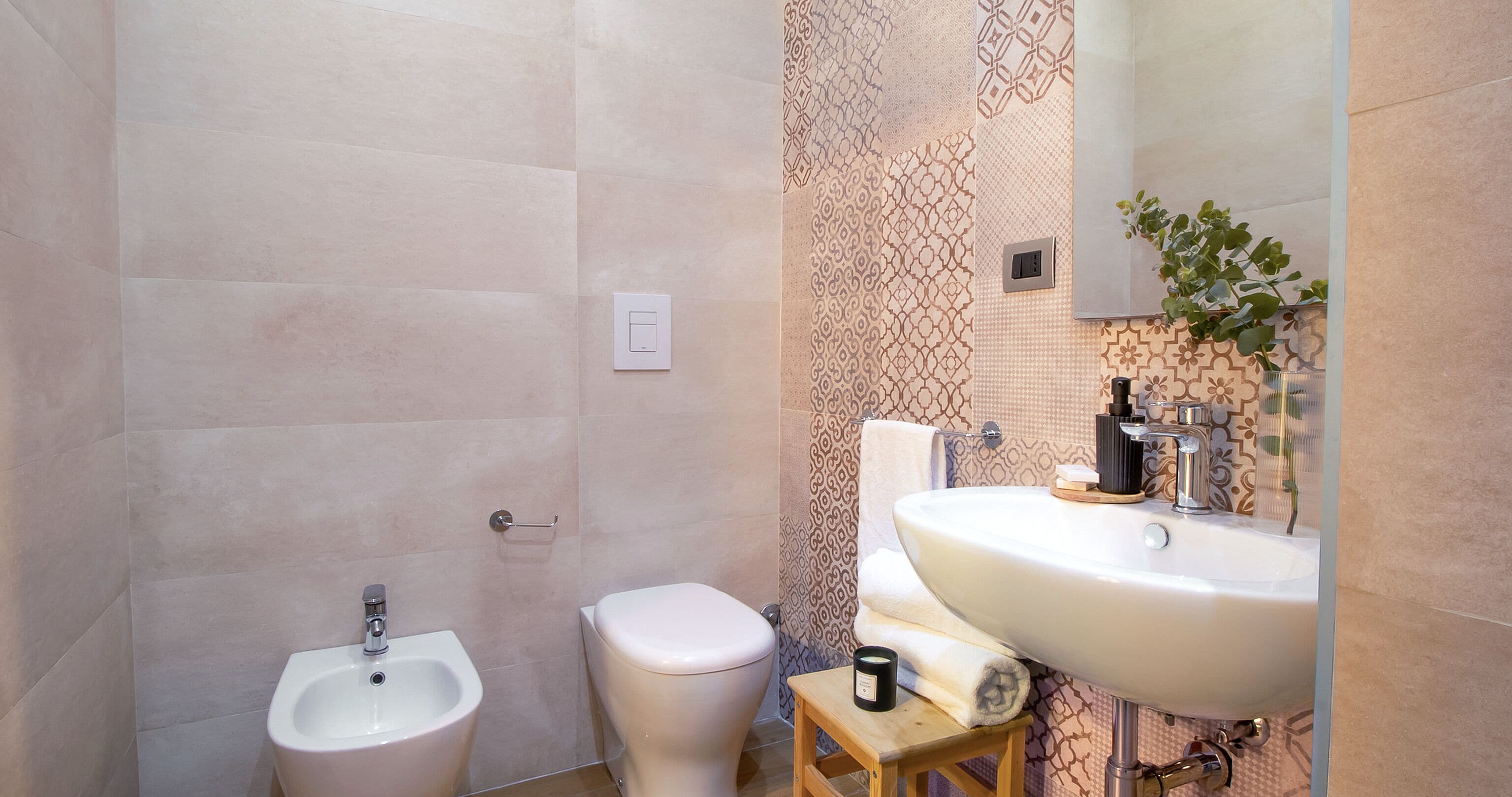 A bathroom with a bidet, toilet, sink, and a small wooden stool.
