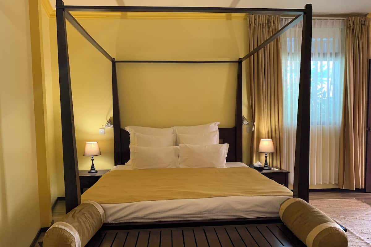 A four-poster bed with a headboard, two bedside tables, and lamps.