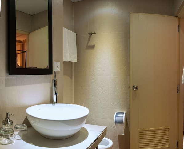 A bathroom with a white sink, a mirror, a towel dispenser, and a toilet. - Sala Boutique Hotel (Malé)