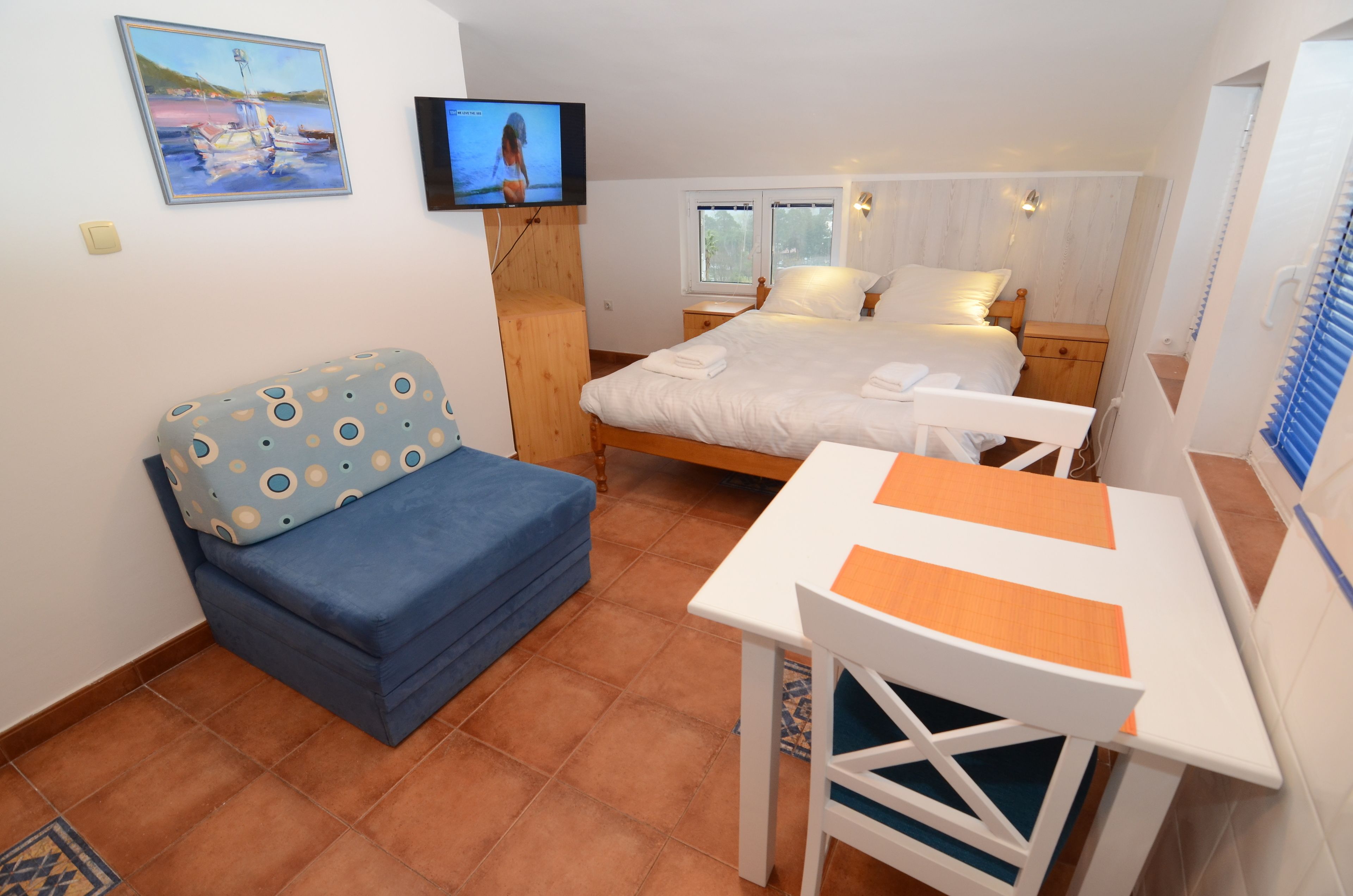 Ein Schlafzimmer mit Bett, Fernseher, Schreibtisch und Stuhl.