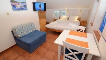 Ein Schlafzimmer mit Bett, Fernseher, Schreibtisch und Stuhl.