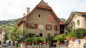Ein traditionelles Gebäude mit schrägem Dach, einem gut sichtbaren Eingang und einem Schild, das es als Hotel kennzeichnet.