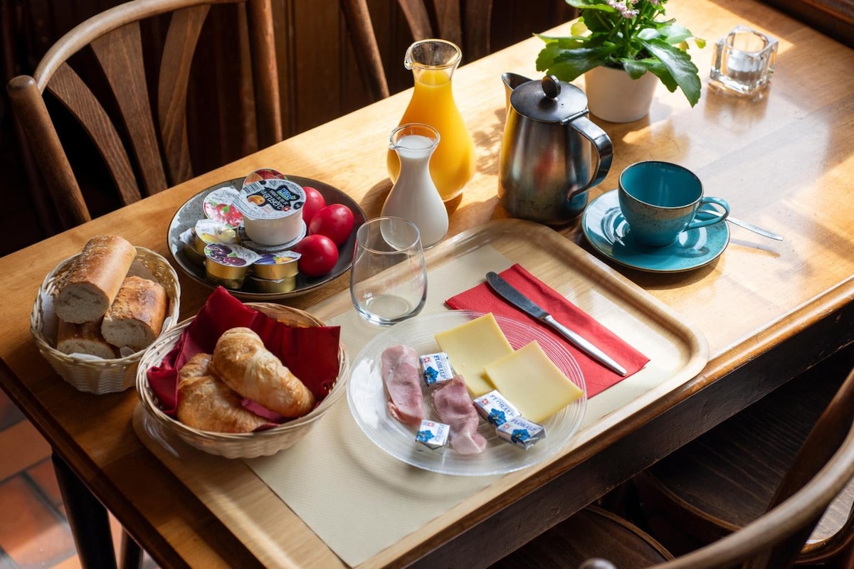 Un plateau de petit-déjeuner avec du pain, des croissants, du fromage, du jambon et du beurre.