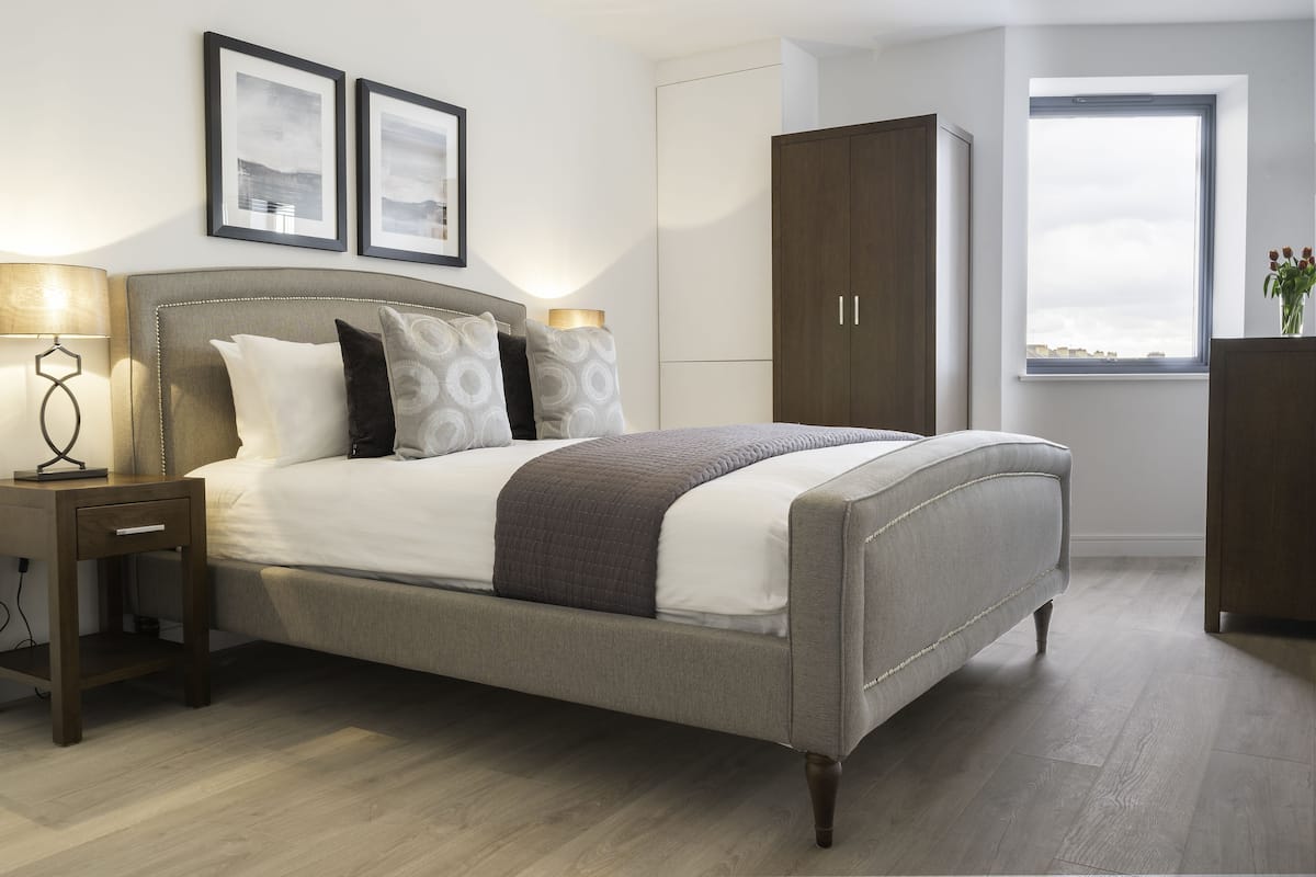 A bedroom with a bed, nightstands, a wardrobe, and framed pictures on the wall.
