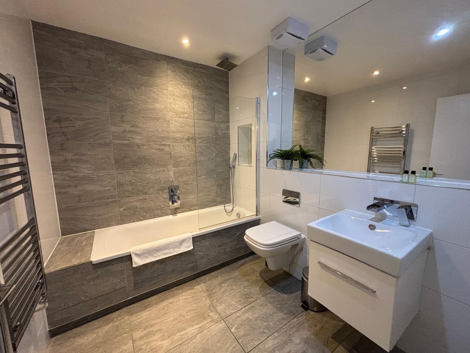 A modern bathroom with a glass-enclosed shower, a white sink, and a toilet.