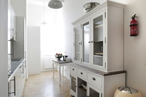 Une cuisine moderne avec des meubles blancs, un plan de travail en bois et une petite table sur laquelle se trouve un saladier rempli de fruits.
