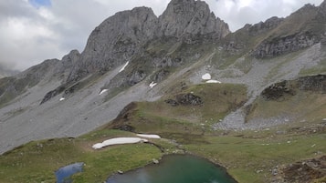 Un paysage montagneux avec un petit lac et quelques zones enneigées.
