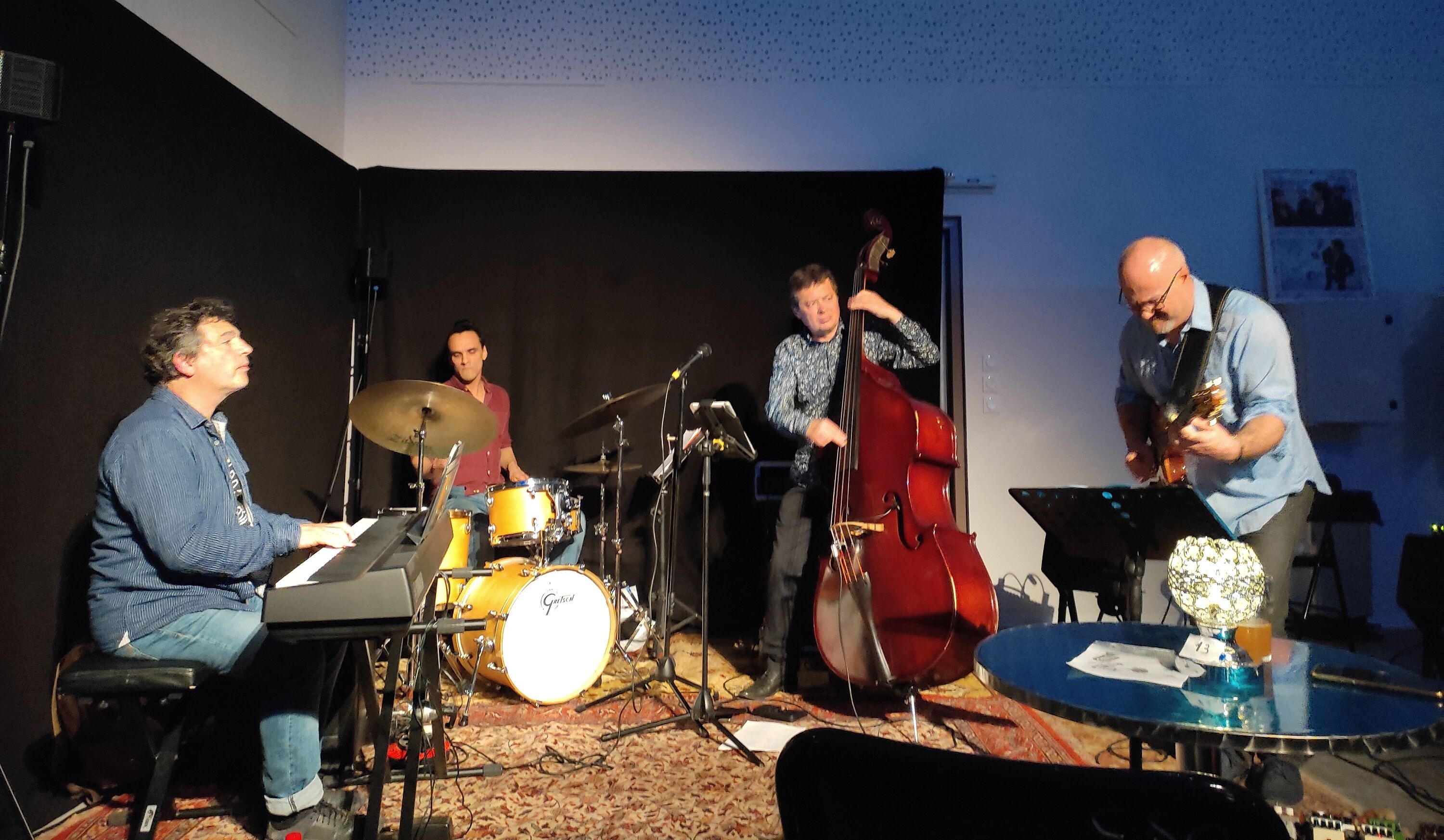 Un groupe de musique se produisant sur une scène, avec un clavier, une batterie et une contrebasse.