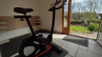 Een overdekte hometrainer in een kamer met uitzicht op een tuin door een glazen deur.