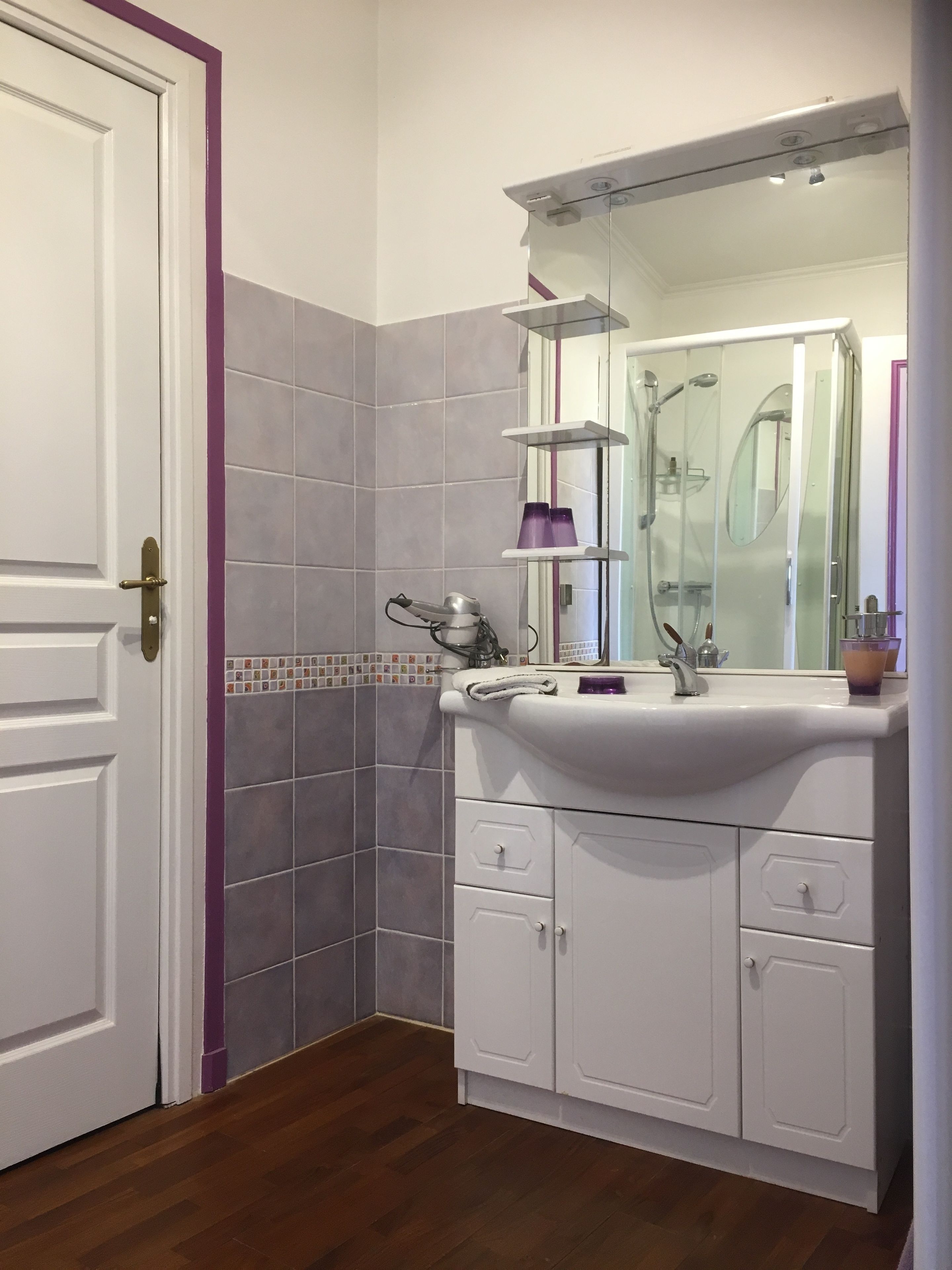 Un baño con lavamanos blanco, un espejo y una ducha.