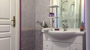 Un baño con lavamanos blanco, un espejo y una ducha.