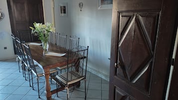 A dining area with a wooden table, metal chairs, a vase with flowers, a chandelier, and a wooden door.