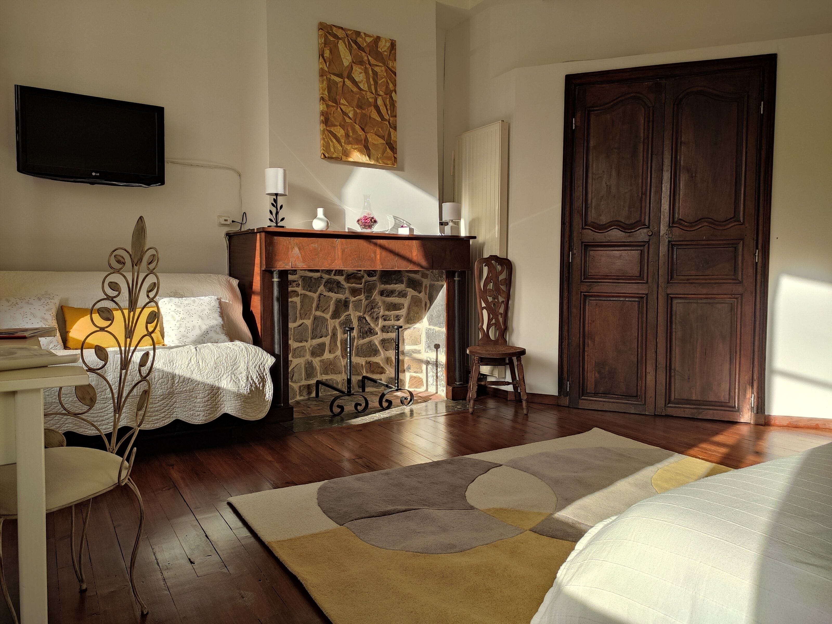 Een kamer met een open haard, een houten deur, een flatscreen televisie en een bed.