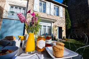 A breakfast table with a variety of food items, a glass of orange juice, and a jar of honey.