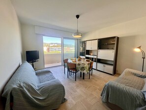 Un espace de vie compact comprenant un coin repas, un téléviseur et un balcon avec vue.