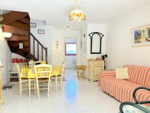 Un salon chaleureux comprenant un coin repas, un escalier et une grande fenêtre.