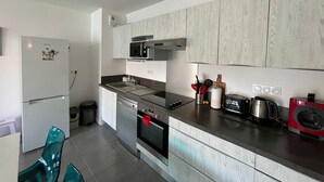 Een moderne keuken met witte kasten, roestvrijstalen apparatuur en een houten plafond.