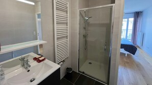 Een badkamer met een witte wastafel, spiegel en een douchecabine van glas.